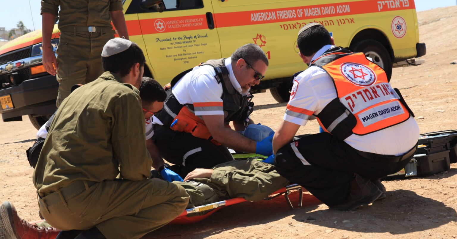 “He Is a Miracle” — Decisive Action Saves Israeli Terror Victim When I first saw him, he was unconscious, and there was a lot of blood on his face and chest,” recalled Yair Schussheim, a MAGEN DAVID ADOM paramedic, upon first seeing Yarin, an Israeli soldier. “I did not think he would survive.” Yarin was on patrol on Highway 60 in Israel when a terrorist struck him with a car. He suffered broken bones, head injuries causing brain damage, and extensive internal bleeding. His leg was nearly severed. There would have been no chance for this young soldier unless one of the most seasoned and well-trained paramedics in the world arrived within moments. Thankfully, that is exactly what happened. Yair Schussheim wasted no time on guesswork and loaded the young man into a Mobile Intensive Care Unit ambulance — essentially an emergency room on wheels — and sped toward the nearest trauma hospital. “I told the ambulance driver, ‘Floor the gas! Don’t stop!’” Yarin’s throat was full of blood, and he struggled for air. Immediately Schussheim and his team ventilated him and opened two IV lines. It was clear to Schussheim that this young man’s life was hanging in the balance. Every intervention and every bit of his experience was brought to bear to keep him alive until he could be transferred to a trauma team. It was a moment-by-moment battle for survival. Schussheim called the hospital on the way so they would be prepared. He explained the situation, the horrific incident, wounds, and everything he was doing to keep Yarin alive. He wanted the surgeons and trauma teams at the ER to be as ready as possible the moment they arrived. But in the paramedic’s heart, he fought back the unthinkable: He’s not going to survive. This young man who had been walking, talking, and defending Israel just minutes earlier was teetering on the brink of death. Schussheim continued employing every intervention possible as he fought for Yarin’s life. Yair Schussheim’s training equipped him to meet this crisis moment. In Israel, emergency medical technicians begin with 200 hours of training to save lives. But as a paramedic, Yair received nearly 10 times as much training. More specifically, he was trained to handle the worst-of-the-worst of all medical emergencies that can occur in the field. It is as if he was trained and handpicked for this moment. It is the support of friends like you that make this training possible. The minutes felt like hours as Schussheim focused all he had ever learned to keep this young soldier alive. And he did. Finally, they arrived at the hospital, and the responsibility for Yarin’s fate passed to the hands of the doctors. Dr. Miklosh Bala, a trauma surgeon at Hadassah Hospital in Jerusalem, credits Yair’s decision-making as the key to the soldier’s survival. According to Dr. Bala, had Yair waited even minutes more, Yarin likely would have died. Yarin himself was shocked at the outcome. “I woke up in the hospital, and I had no idea how I am alive.” His mother, Riki, was overcome with grief at seeing her son. “I asked the entire nation of Israel to pray.” But her cries of despair turned to tears of joy as Yarin began to slowly recover. “He woke up against all odds. Thank God. And he was able to speak.” Yair visited Yarin after he gained consciousness. “I saw him and told him, ‘Now is the beginning of your new life; don’t give up.’” Yarin took his rescuer’s words to heart. While waking, speaking, and breathing on his own were the first miracles, next came standing on his own. So terrible were his injuries that he struggled to stay up on his own two feet. Yarin went to therapy every day, pushing through the pain and the failure. But he would not give up, even after falling and falling and falling again. His remarkable resilience was eventually rewarded when, one day, he spurred himself on with powerful words of resolve and determination: “No! Enough! I must stand!” Yarin endured months of grueling rehabilitation, and six months after the attack, he was almost fully recovered and able to attend a ceremony honoring the lifesaving paramedic. “A lot of patients do not survive those kinds of terrorist acts,” Schussheim said. “But he just didn’t give up; that’s all.” For Yarin, it was the least he could do for a man who he now considers family. “Yair is not just the paramedic who saved my life,” he said. “He is like my brother. I did not expect a connection like this.” Give to Help Save Lives in Israel The training Israel’s paramedics receive often means the difference between life and death. Of MAGEN DAVID ADOM’s corps of about 37,500 EMTs and volunteers, about 1,000 are paramedics. This elite group of frontline medical professionals undergoes more than 1,500 hours of rigorous training to care for those on the verge of life and death. There are many willing to devote their lives to this calling, but they CANNOT serve without the proper training and medical supplies. Your support can make that possible. Every trained and equipped paramedic can save thousands of lives over many years of service. Almost all that MAGEN DAVID ADOM does in Israel, from being responsible for the nation’s emergency services and blood supply to training its paramedics is made possible by generous donations from individuals who love Israel, just like you. Help Saves Lives As the most skilled medical professionals in the field, MAGEN DAVID ADOM paramedics work tirelessly, day in and day out, to answer the calls for help and save victims of the most horrific terror attacks, accidents, and emergencies. Many share the same perspective as Yair Schussheim. “People come into the world to some purpose, and my purpose is to help someone,” he said. “This is our destiny.” While many have praised Yair’s fast and lifesaving actions, he is quick to deflect the praise. “Yarin taught me that everything is possible because he is a miracle.” You can be a part of a miracle in Israel today when you give to support the lifesaving work of MAGEN DAVID ADOM. Your support makes it possible to equip, train, and dispatch paramedics in Israel every time there is a crisis. Donate Now MAGEN DAVID ADOM, Israel’s national Red Cross society, provides emergency medical care and ambulance services for victims of terror, natural disasters, automobile accidents, and other emergencies in Israel. It is also responsible for the nation’s blood supply. MAGEN DAVID ADOM is saving lives in Israel every day.