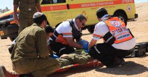 When I first saw him, he was unconscious, and there was a lot of blood on his face and chest,” recalled Yair Schussheim, a MAGEN DAVID ADOM paramedic, upon first seeing Yarin, an Israeli soldier. “I did not think he would survive.” Yarin was on patrol on Highway 60 in Israel when a terrorist struck him with a car. He suffered broken bones, head injuries causing brain damage, and extensive internal bleeding. His leg was nearly severed. There would have been no chance for this young soldier unless one of the most seasoned and well-trained paramedics in the world arrived within moments. Thankfully, that is exactly what happened. Yair Schussheim wasted no time on guesswork and loaded the young man into a Mobile Intensive Care Unit ambulance — essentially an emergency room on wheels — and sped toward the nearest trauma hospital. “I told the ambulance driver, ‘Floor the gas! Don’t stop!’” Yarin’s throat was full of blood, and he struggled for air. Immediately Schussheim and his team ventilated him and opened two IV lines. It was clear to Schussheim that this young man’s life was hanging in the balance. Every intervention and every bit of his experience was brought to bear to keep him alive until he could be transferred to a trauma team. It was a moment-by-moment battle for survival. Schussheim called the hospital on the way so they would be prepared. He explained the situation, the horrific incident, wounds, and everything he was doing to keep Yarin alive. He wanted the surgeons and trauma teams at the ER to be as ready as possible the moment they arrived. But in the paramedic’s heart, he fought back the unthinkable: He’s not going to survive. This young man who had been walking, talking, and defending Israel just minutes earlier was teetering on the brink of death. Schussheim continued employing every intervention possible as he fought for Yarin’s life. Yair Schussheim’s training equipped him to meet this crisis moment. In Israel, emergency medical technicians begin with 200 hours of training to save lives. But as a paramedic, Yair received nearly 10 times as much training. More specifically, he was trained to handle the worst-of-the-worst of all medical emergencies that can occur in the field. It is as if he was trained and handpicked for this moment. It is the support of friends like you that make this training possible. The minutes felt like hours as Schussheim focused all he had ever learned to keep this young soldier alive. And he did. Finally, they arrived at the hospital, and the responsibility for Yarin’s fate passed to the hands of the doctors. Dr. Miklosh Bala, a trauma surgeon at Hadassah Hospital in Jerusalem, credits Yair’s decision-making as the key to the soldier’s survival. According to Dr. Bala, had Yair waited even minutes more, Yarin likely would have died. Yarin himself was shocked at the outcome. “I woke up in the hospital, and I had no idea how I am alive.” His mother, Riki, was overcome with grief at seeing her son. “I asked the entire nation of Israel to pray.” But her cries of despair turned to tears of joy as Yarin began to slowly recover. “He woke up against all odds. Thank God. And he was able to speak.” Yair visited Yarin after he gained consciousness. “I saw him and told him, ‘Now is the beginning of your new life; don’t give up.’” Yarin took his rescuer’s words to heart. While waking, speaking, and breathing on his own were the first miracles, next came standing on his own. So terrible were his injuries that he struggled to stay up on his own two feet. Yarin went to therapy every day, pushing through the pain and the failure. But he would not give up, even after falling and falling and falling again. His remarkable resilience was eventually rewarded when, one day, he spurred himself on with powerful words of resolve and determination: “No! Enough! I must stand!” Yarin endured months of grueling rehabilitation, and six months after the attack, he was almost fully recovered and able to attend a ceremony honoring the lifesaving paramedic. “A lot of patients do not survive those kinds of terrorist acts,” Schussheim said. “But he just didn’t give up; that’s all.” For Yarin, it was the least he could do for a man who he now considers family. “Yair is not just the paramedic who saved my life,” he said. “He is like my brother. I did not expect a connection like this.” Give to Help Save Lives in Israel The training Israel’s paramedics receive often means the difference between life and death. Of MAGEN DAVID ADOM’s corps of about 37,500 EMTs and volunteers, about 1,000 are paramedics. This elite group of frontline medical professionals undergoes more than 1,500 hours of rigorous training to care for those on the verge of life and death. There are many willing to devote their lives to this calling, but they CANNOT serve without the proper training and medical supplies. Your support can make that possible. Every trained and equipped paramedic can save thousands of lives over many years of service. Almost all that MAGEN DAVID ADOM does in Israel, from being responsible for the nation’s emergency services and blood supply to training its paramedics is made possible by generous donations from individuals who love Israel, just like you. Help Saves Lives As the most skilled medical professionals in the field, MAGEN DAVID ADOM paramedics work tirelessly, day in and day out, to answer the calls for help and save victims of the most horrific terror attacks, accidents, and emergencies. Many share the same perspective as Yair Schussheim. “People come into the world to some purpose, and my purpose is to help someone,” he said. “This is our destiny.” While many have praised Yair’s fast and lifesaving actions, he is quick to deflect the praise. “Yarin taught me that everything is possible because he is a miracle.” You can be a part of a miracle in Israel today when you give to support the lifesaving work of MAGEN DAVID ADOM. Your support makes it possible to equip, train, and dispatch paramedics in Israel every time there is a crisis. Donate Now MAGEN DAVID ADOM, Israel’s national Red Cross society, provides emergency medical care and ambulance services for victims of terror, natural disasters, automobile accidents, and other emergencies in Israel. It is also responsible for the nation’s blood supply. MAGEN DAVID ADOM is saving lives in Israel every day.